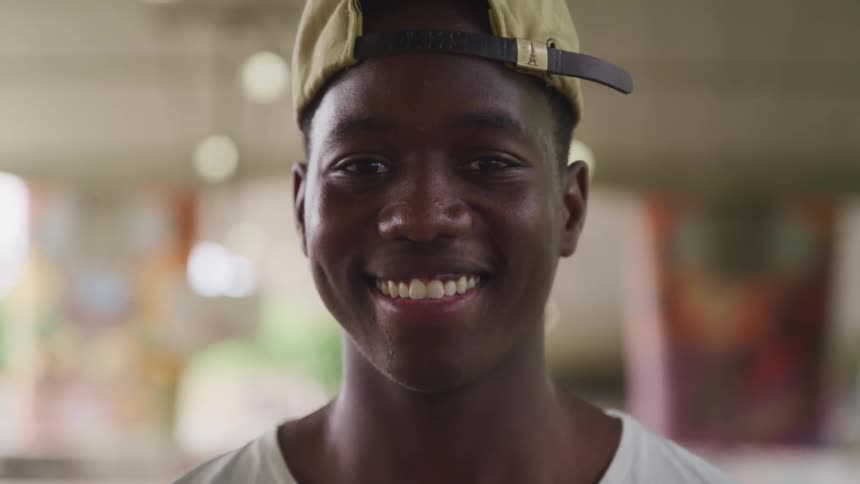 Young man wearing a baseball cap looking at the camera smiling