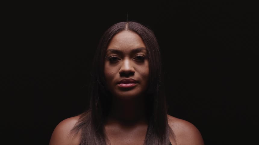 Young woman standing in a dark room looks up at the camera