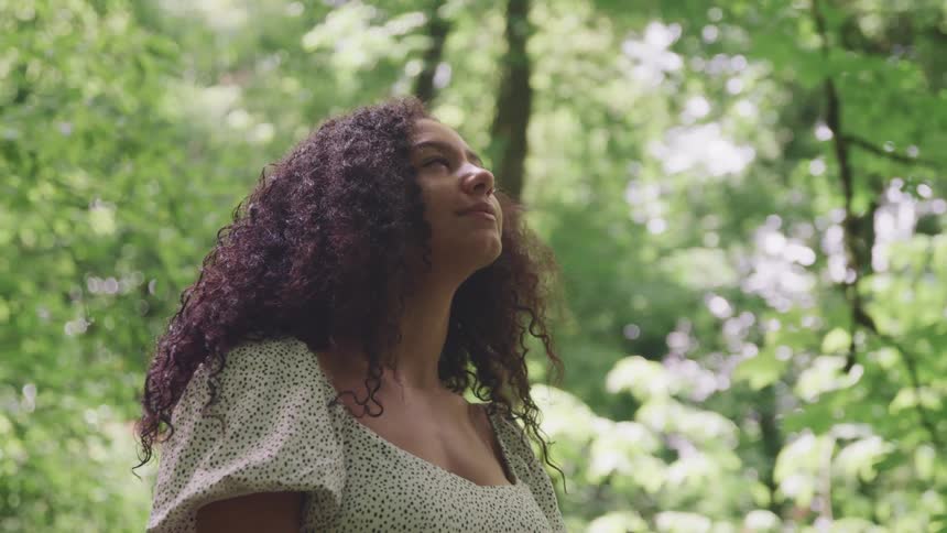 Woman standing in a forest looking up