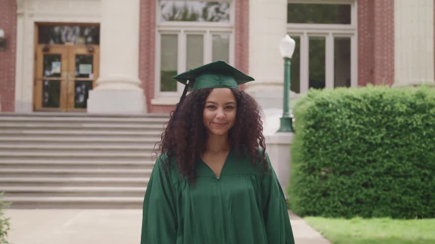 A woman with a cap and gown standing in front of a building