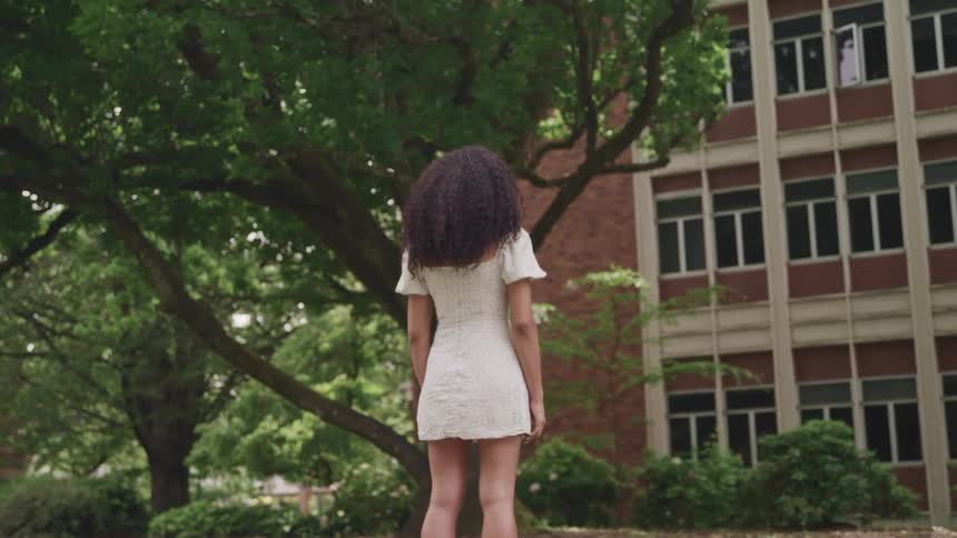 A woman is standing outside by the building