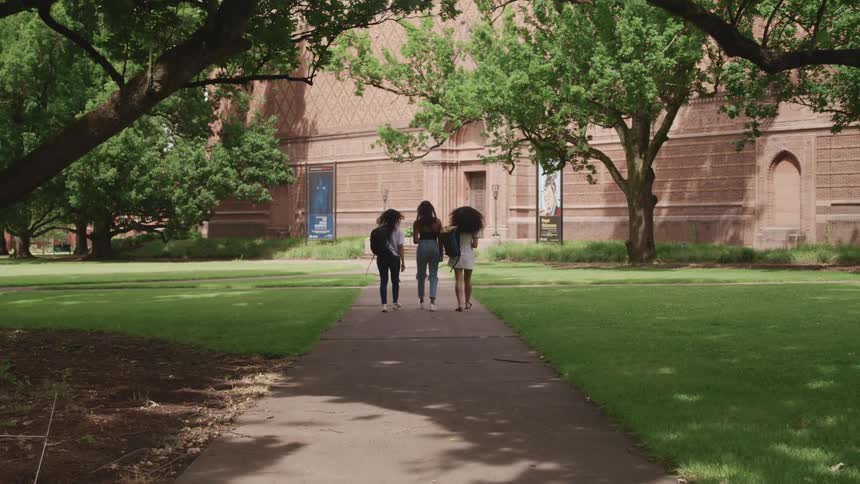 A group of three women walking down a sidewalk