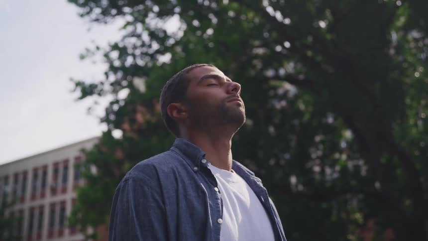 A man standing outdoors with his eyes closed