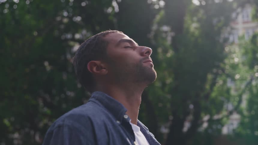 Sunlight rays reflecting on a young mans face looking up