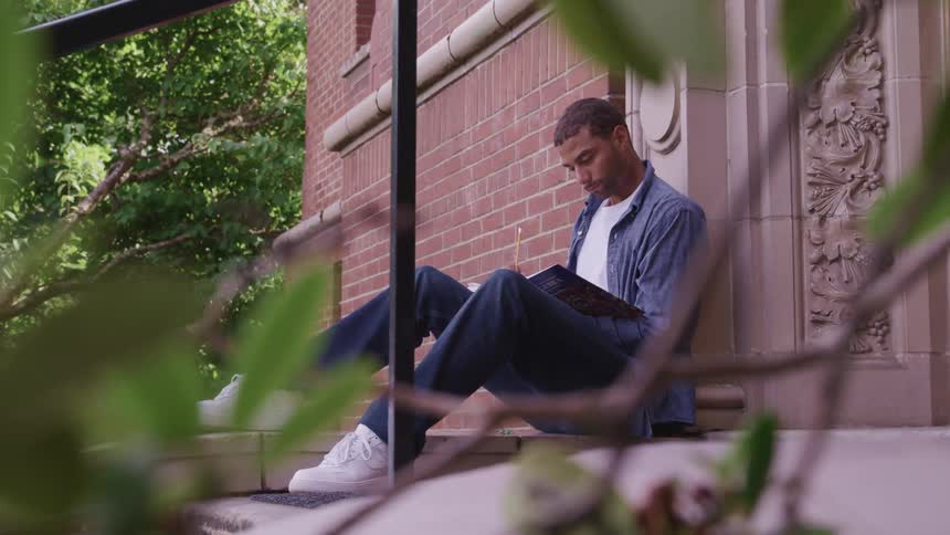 A college student studies while sitting on steps outside a building