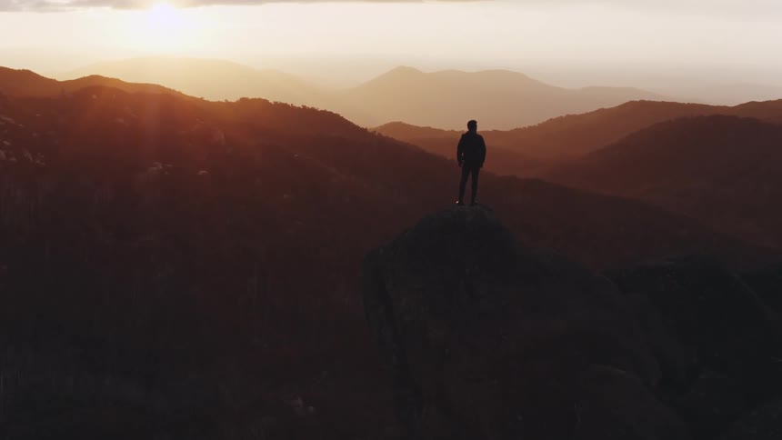 Man standing on the edge of a cliff looking at the horizon