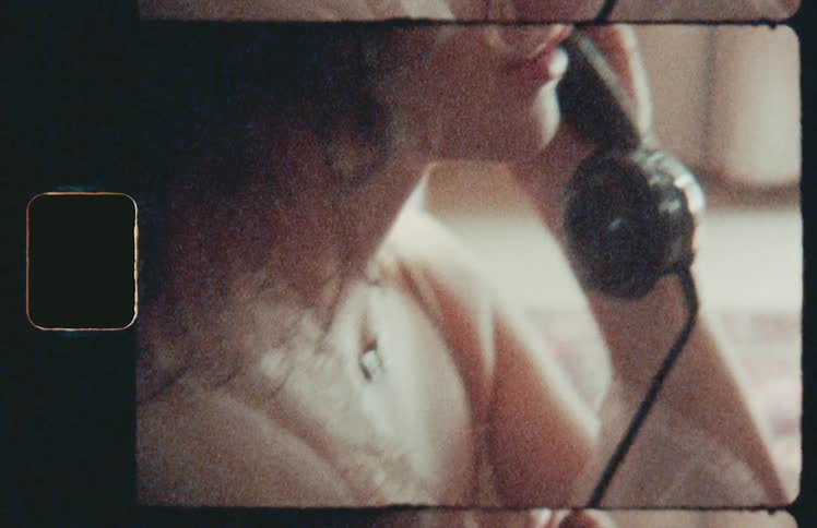 A woman with a tattoo on the inside of her wrist holds a retro handset as she talks on the phone