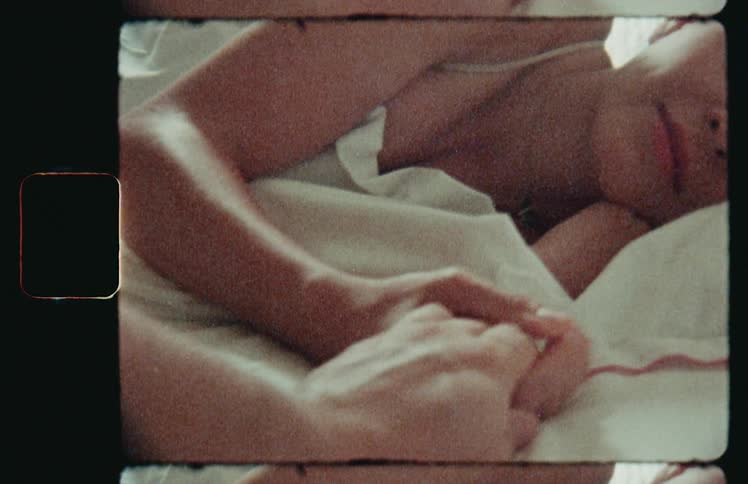 A man and woman hold hands in bed