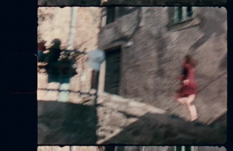 A woman running up a stone staircase in an alleyway between stone buildings