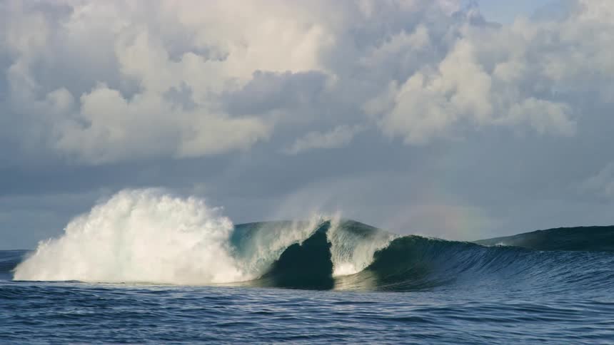 Waves roll in splashing under a cloudy sky