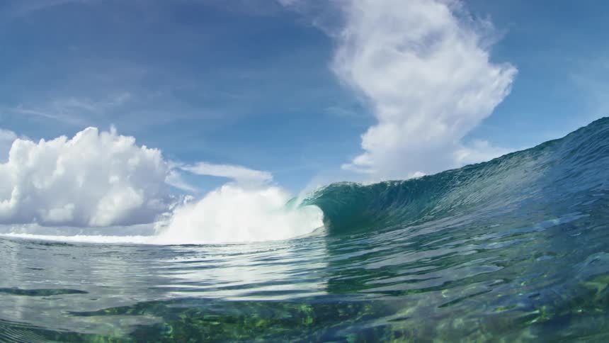 Huge wave rolls overhead under a cloudy sky