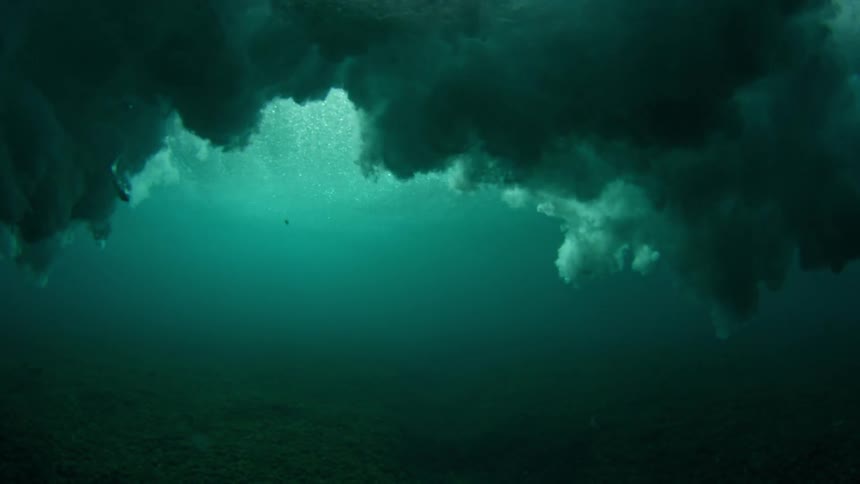 Sun shines on a wave splashing and rolling in overhead and an underwater view