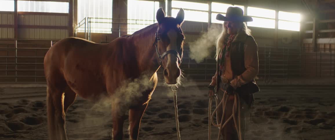 Woman standing next to horse and smiling in barn