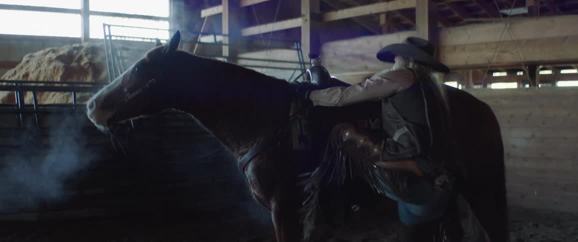 Woman leads horse into stable and mounts for riding