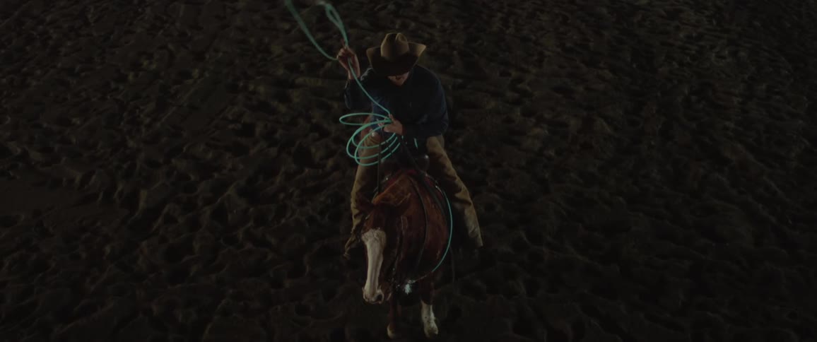 Cowboy mounted on a horse swings a lasso over his head