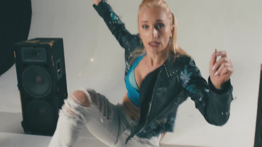 Young blonde woman energetically dancing in front of speakers