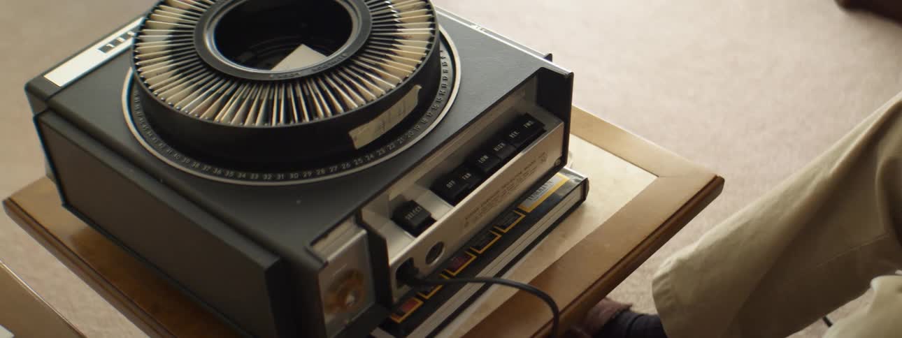 Elderly man arranging slides on a carrousel projector in the living room at home