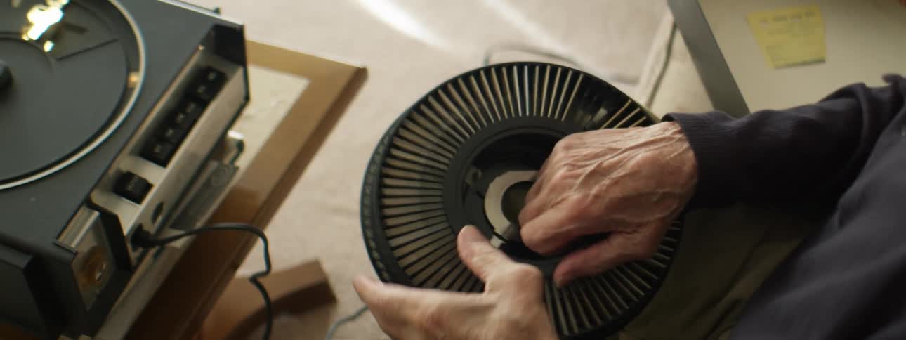 Elderly man dissasembling a slide carrousel projector at home