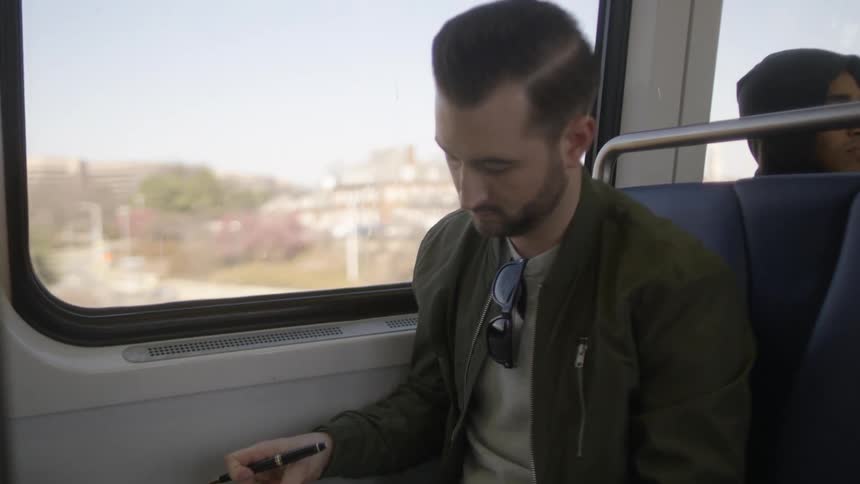 A man looking at a book on a train