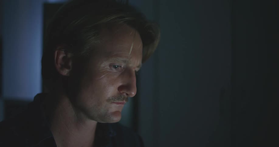 A man deep in thought while sitting in a dark room