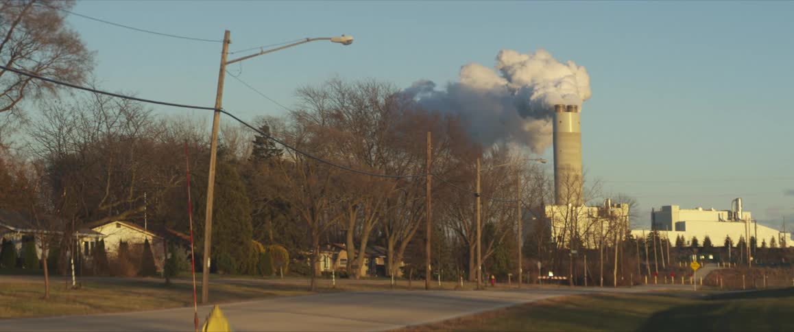 Smoke billows from a building smoke stack near homes and roads