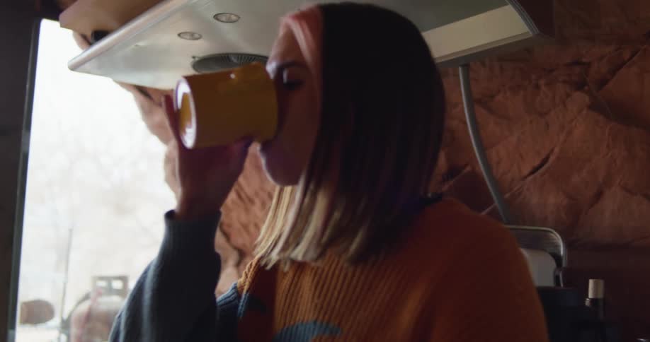 Young woman drinking a hot beverage on the kitchen of a house inside a cave