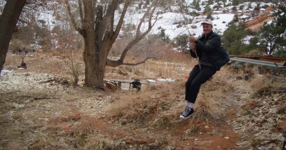 Man using a swing hanging from a tree in a rural area