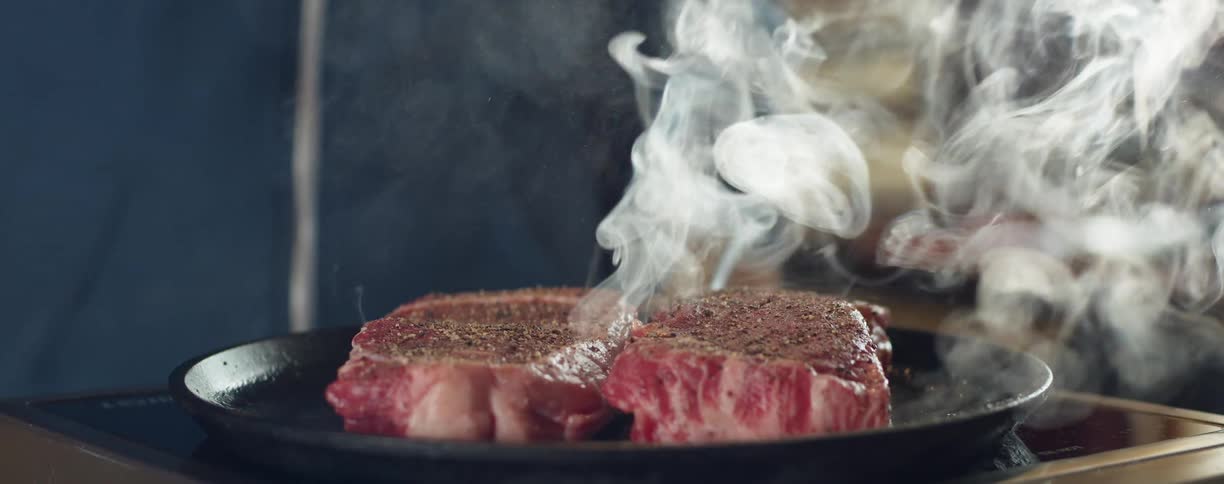 A man that is cooking some steaks