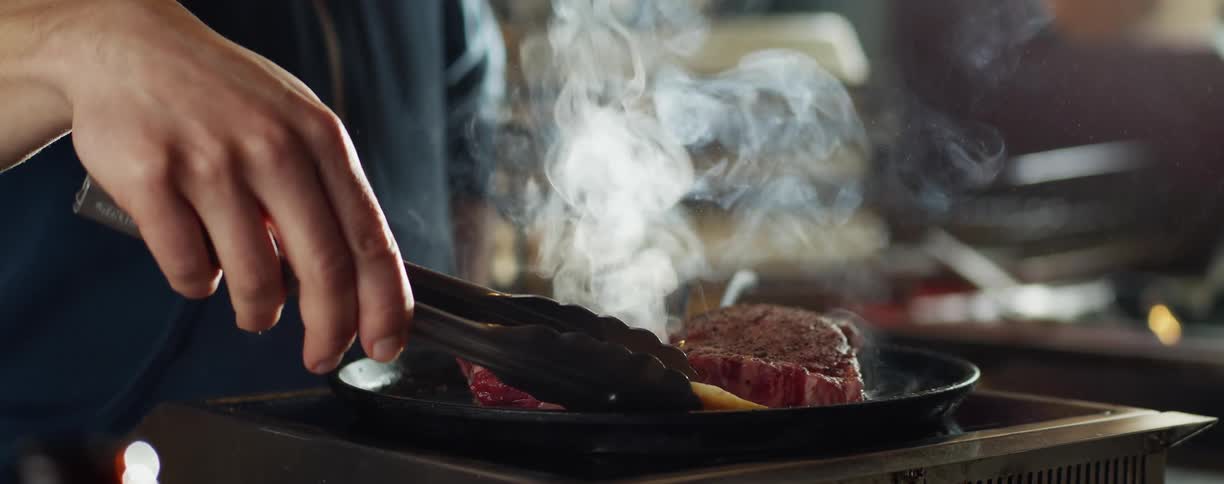 A man cooking steaks on a pan