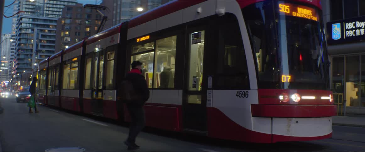 Passengers boarding an electric trolleybus driving on the city streets at night