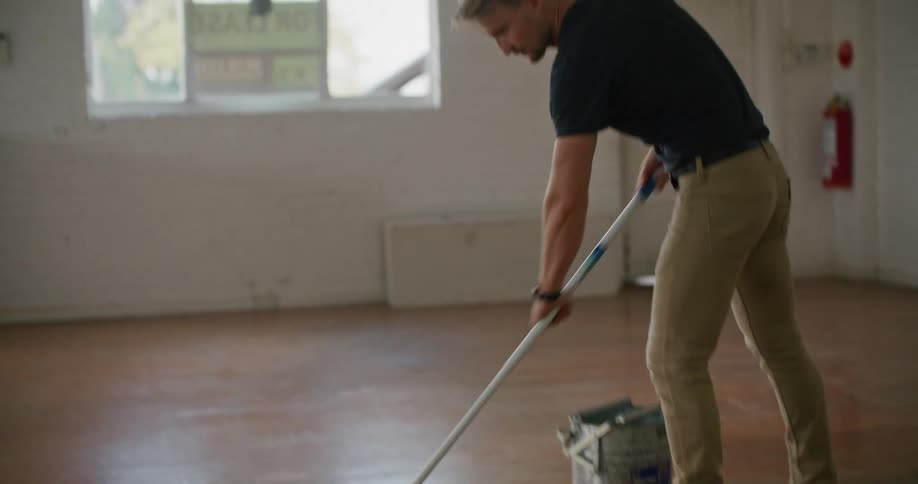 A man that is mopping the floor of a room