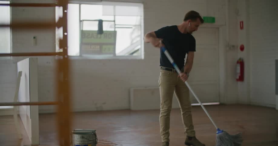 A man wears ear buds as he mops inside an empty store