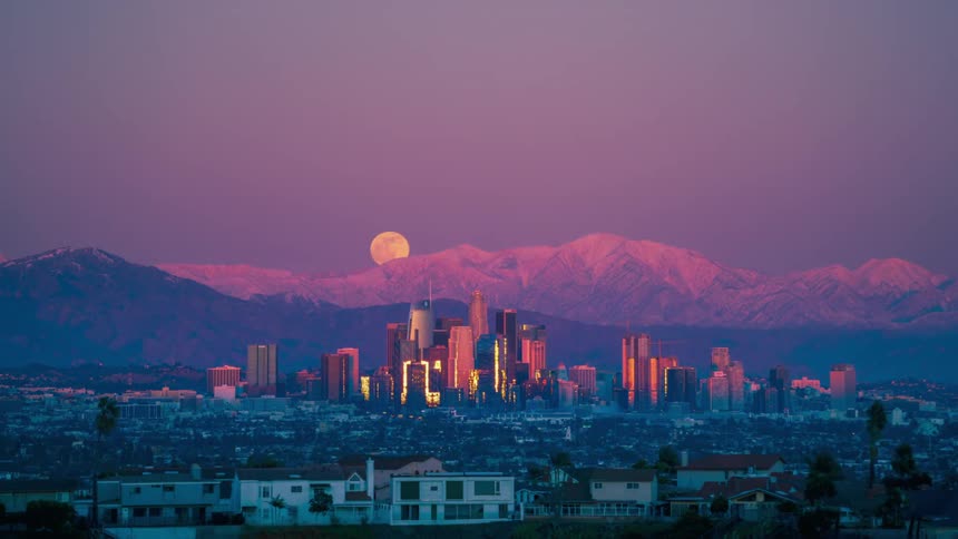 The full moon rises over a metropolis as the sunsets