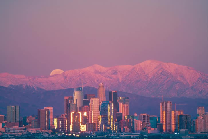 Time lapse of the full moon rising over a city near a mountain