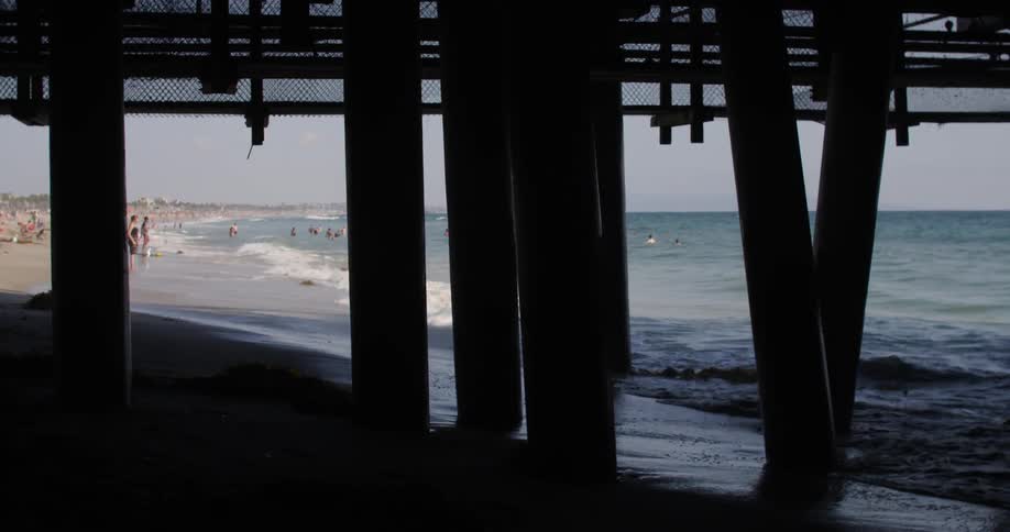 Beach view underneath a tall dock