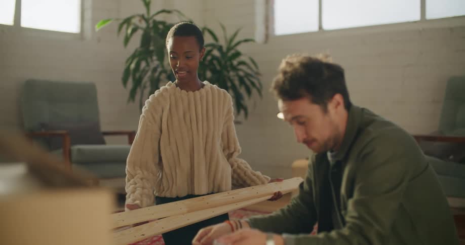 Young couple sitting in the living room floor asssembling furniture