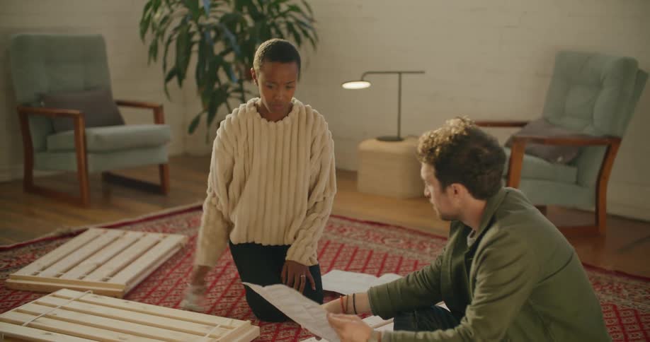 A couple go over instructions as they try to build furniture in their living room