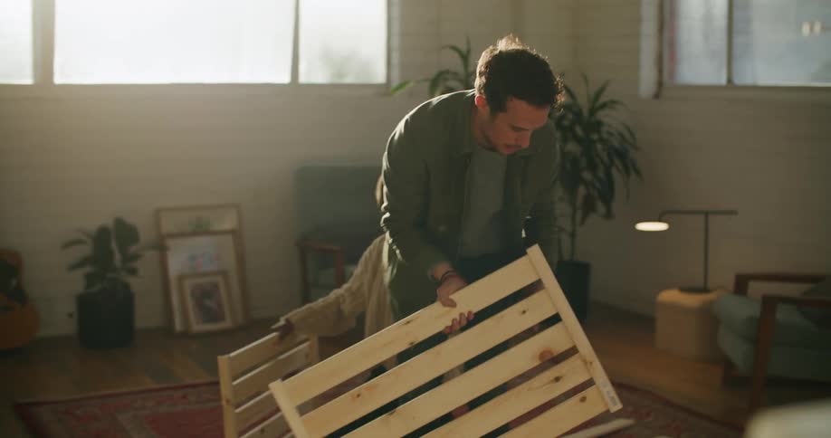 A man and a woman on the floor putting together furniture with plants and walls in the background