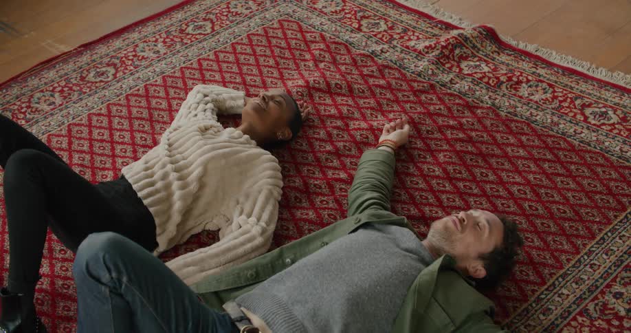 A man and a woman in a room laying on the floor on a carpet