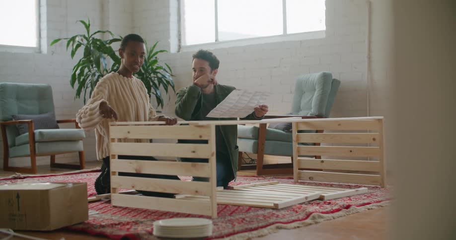 A man and a woman on the floor on a carpet with chairs and walls in the background