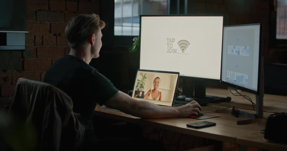 A man sitting on a chair at a desk with a laptop and computer