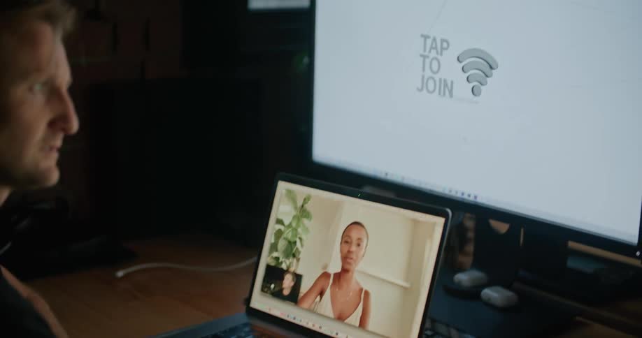 Man and woman video call while man works on desktop computer
