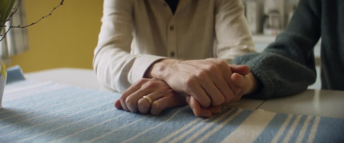 Couple sits at table holding hands