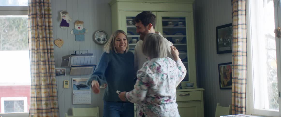A mother and father hugging a grandmother