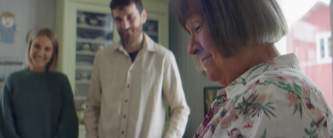 A father and mother showing a picture of an ultrasound to a grandmother