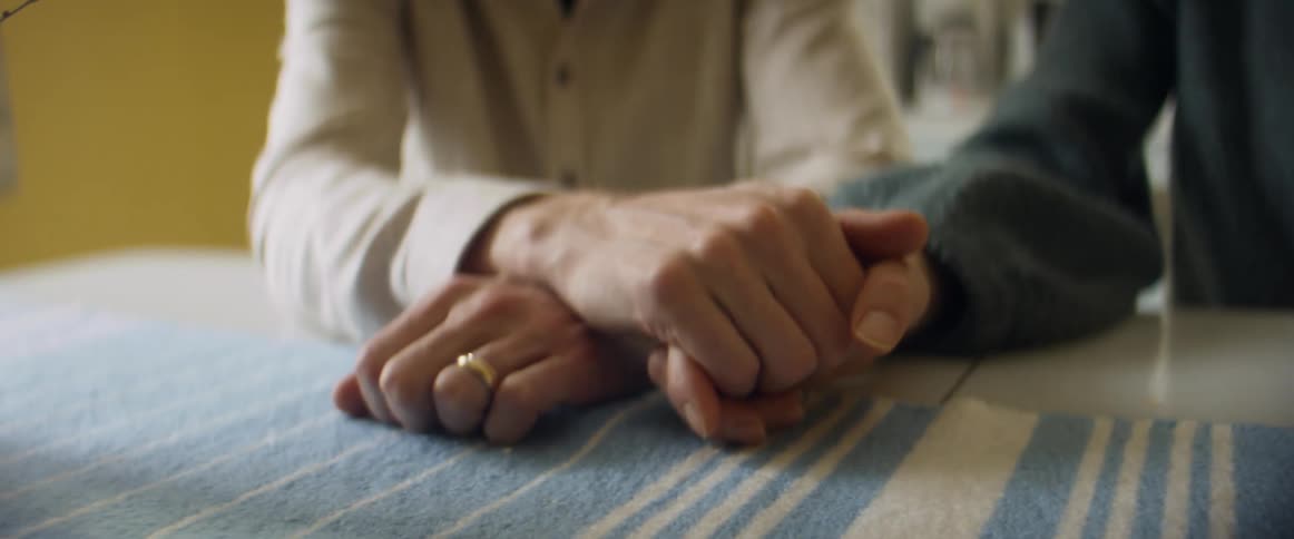 Married couple sit at table with runner holding hands