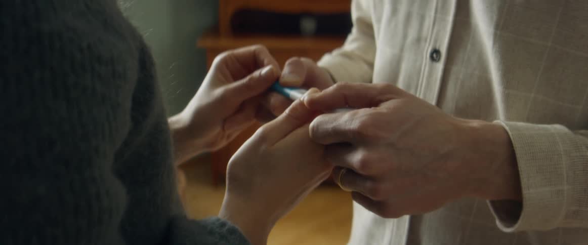 A man and a woman in a room holding a pregnancy test with a wall and window in the background