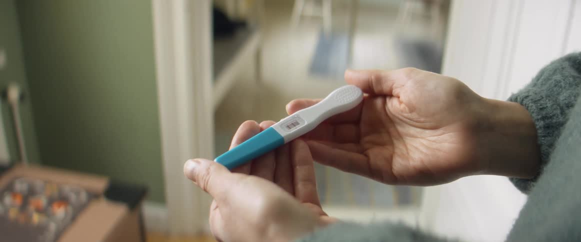 A womans hands hold a positive pregnancy test
