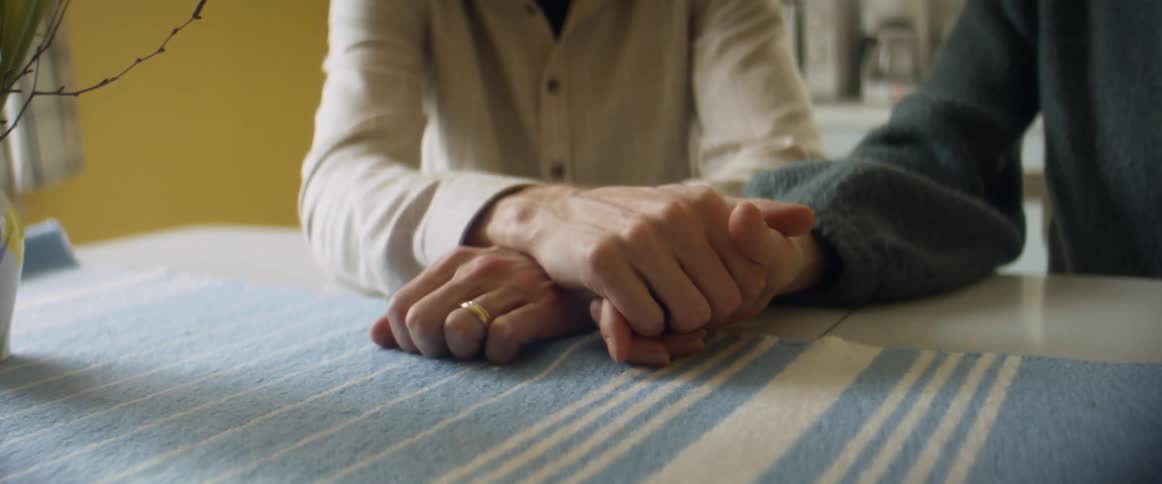 Couple sits holding hands at table covered with table runner