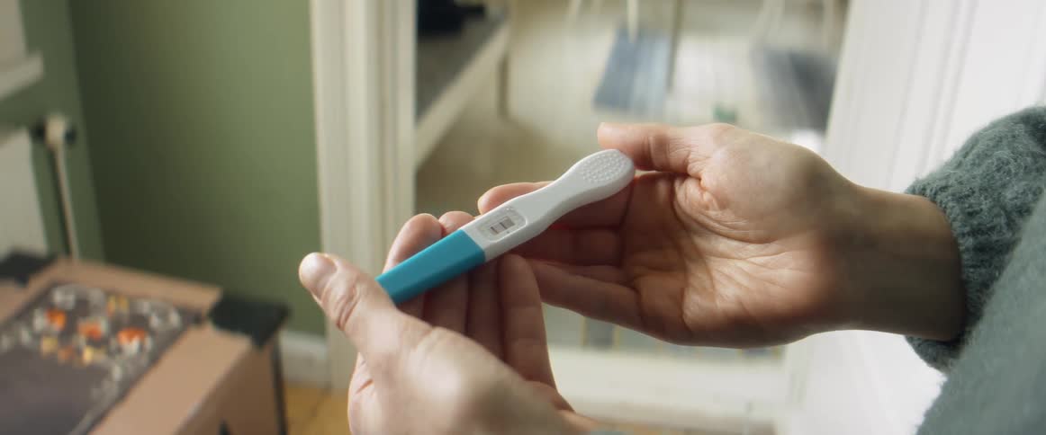 A woman holds and reads the results of a pregnancy test